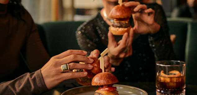 Una pareja comiendo minihamburguesas en un restaurante